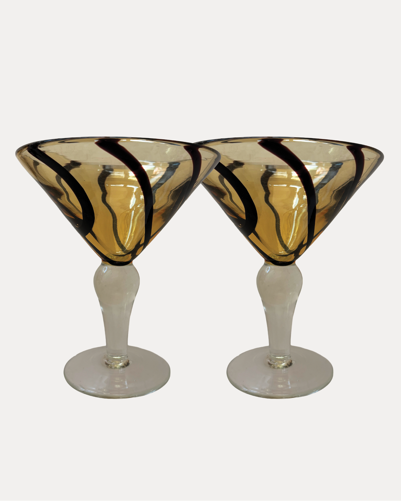 Two triangular martini glasses with black and gold design on a white background